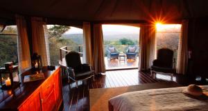 a bedroom with a bed and a balcony with chairs at Thanda Safari in Hluhluwe