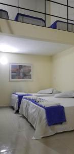 Cette chambre comprend 3 lits avec des couvertures bleues. dans l'établissement Villa Solarium Pousada, à Cabo Frio