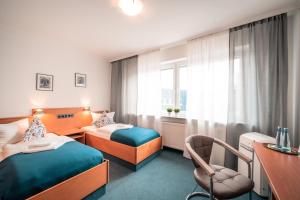 una habitación de hotel con 2 camas y una silla en Airport Lounge Hotel Düsseldorf, en Düsseldorf