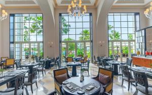 un restaurante con mesas, sillas y ventanas grandes en The Danna Langkawi - A Member of Small Luxury Hotels of the World, en Pantai Kok