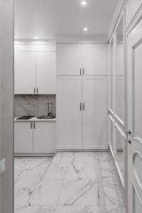 een witte keuken met witte kasten en een wastafel bij Royal Tower VIP Smart Apartments 1 in Kiev
