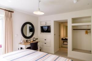 a bedroom with a bed and a desk and a mirror at The Plume of Feathers in Mitchell