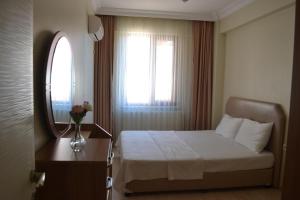 1 dormitorio con cama, espejo y ventana en Almasa Suite Aparts, en Termal