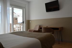 a bedroom with a bed and a desk and a television at Hotel Airiños 3* in Cangas de Morrazo