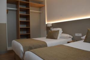 a hotel room with two beds and a book shelf at Hotel Airiños 3* in Cangas de Morrazo