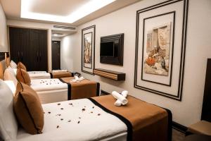 ein Hotelzimmer mit vier Betten und einem Flachbildfernseher in der Unterkunft Dimen Hotel in Bursa