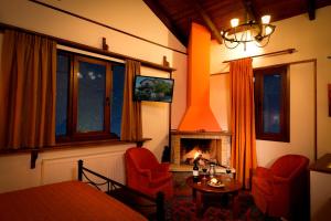 a living room with a fireplace and red chairs at Dryas Guesthouse in Polydrossos