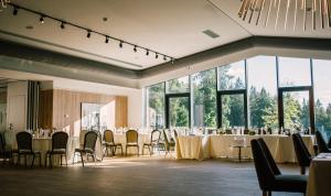 un salón de banquetes con mesas, sillas y ventanas en Complex Hotelier COTA O MIE, en Sinaia