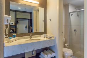 a bathroom with a sink and a toilet and a mirror at Holiday Inn Express Maceió, an IHG Hotel in Maceió