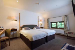 a bedroom with a large bed and a desk and a chair at Golden Lion Hotel in Rugby