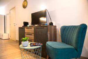 a living room with a blue chair and a tv at Center Design Residence in Brussels