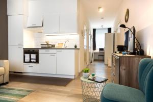 a kitchen with white cabinets and a living room at Center Design Residence in Brussels