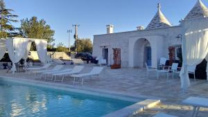 um grupo de cadeiras e uma piscina com um edifício em TRULLI COLIBRI' em Locorotondo