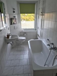 a white bathroom with a tub and a sink at Ferienwohnung mit Seeblick in Brandenburg an der Havel