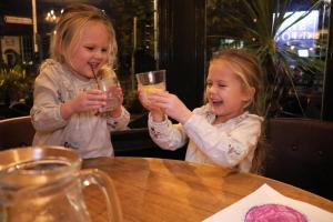 two little girls sitting at a table holding up glasses at The Bold Hotel; BW Signature Collection in Southport