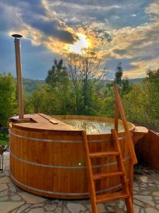una vasca da bagno in legno, situata accanto a una sedia in legno di Pensiunea PORTAS RESORT a Slănic