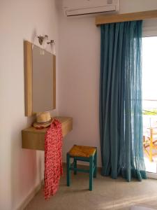 a mirror and a stool in a room with a window at Calypso in Agia Roumeli