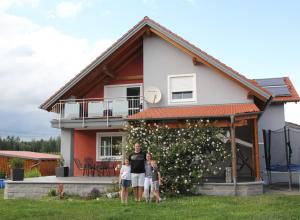 a woman and two children standing in front of a house at Ferienwohnung Leibl in Oberviechtach