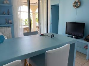 a blue room with a desk with chairs and a tv at Appartamentino Celeste in Porto Recanati