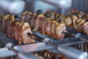 a bunch of bacon and meat on a grill at Rodizio Hill Resort in Cluj-Napoca