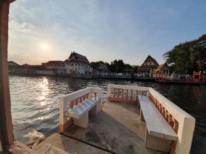 two benches sitting on a dock next to the water at KINN Stay50 Bangkok in Bangkok Yai