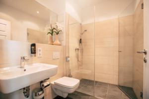 a bathroom with a sink and a toilet and a shower at Luga Homes - Stadthaus in Leipzig +22 photos