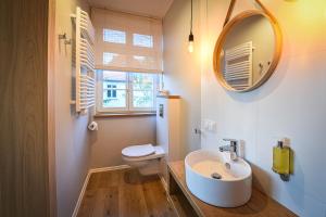 a bathroom with a sink and a toilet and a mirror at Villa Bałtycka in Gdańsk