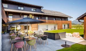 a patio with tables and chairs and an umbrella at Hotel Das Essigmanngut in Anif