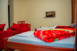 a bed with a red blanket on top of it at Kilimanjaro White House Hotel in Moshi