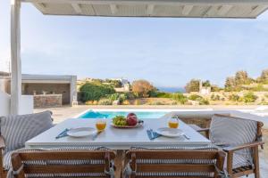 a table with a bowl of fruit and two glasses of orange juice at Sea Wind Villas and Suites in Tourlos