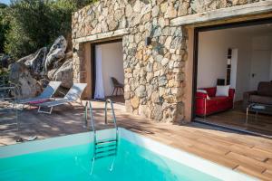 een huis met een zwembad met een stenen muur bij Domaine Valle Doniche in Olmeto