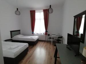 Habitación con 2 camas, mesa y TV. en Villa Grudziądz, en Grudziądz