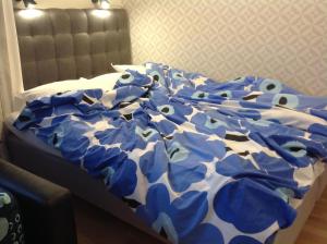 an unmade bed with a blue blanket and pillows at Lumi City Apartment in Levi