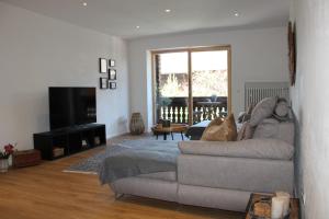 uma sala de estar com um sofá e uma televisão em Ferienwohnung Oberschopper em Flintsbach