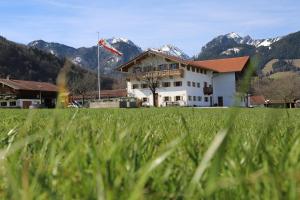 a house in a field with mountains in the background at Ferienwohnung Fischerhof in Flintsbach