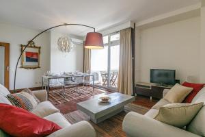 a living room with couches and a television and a table at LovelyStay - Spacious 3BR Flat with AC and Balcony in Porto
