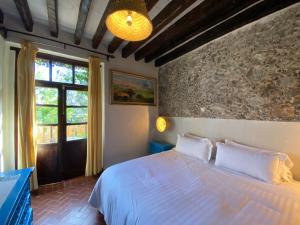 Posada Colibri - Hotel & Spa في سان جان تيوتيهواكان: غرفة نوم بسرير وجدار حجري