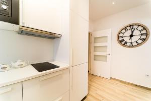 a kitchen with white cabinets and a clock on the wall at Suite Capitán 3 in Cádiz
