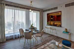 a dining room with a table and chairs and a large window at Durrani Homes - Designer 2BR Apt with stunning Burj khalifa and Fountain View in Dubai