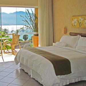 a bedroom with a bed with a view of the ocean at Hotel Itapemar - Ilhabela in Ilhabela