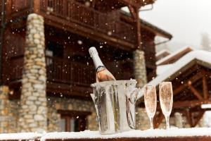 a bottle of champagne in a snow storm with wine glasses at Hotel La Foret in Peisey-Nancroix