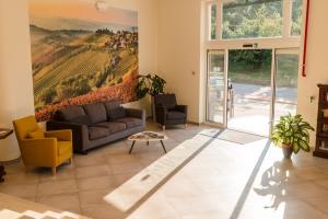 a living room with a couch and a painting of a vineyard at Hotel & Wellness Stella Delle Langhe in Govone