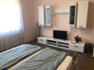 ein Wohnzimmer mit einem TV, einem Bett und einem TV-Stand in der Unterkunft Emese vendégház in Mezőpeterd