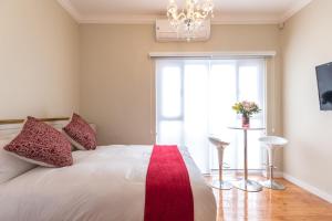 een slaapkamer met een wit bed met rode kussens en een raam bij Vesper Apartments in Kaapstad