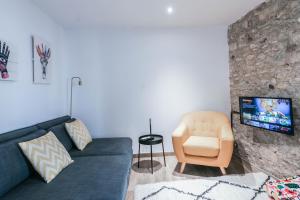 sala de estar con sofá azul y silla en Tresor Boutique Apartment, en Girona