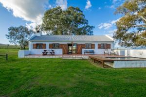 a small white house with a large yard at Denneboom Vineyards and Wildlife in Paarl