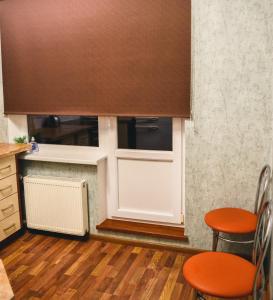 a kitchen with a cupboard and two orange chairs at Cosy and Charming apartment in Alūksne