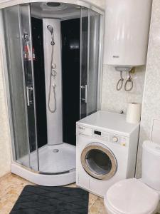 a bathroom with a shower and a washing machine at Cosy and Charming apartment in Alūksne
