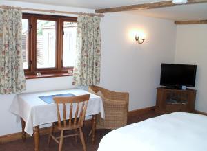 a room with a table and a bed and a television at The Courtyard, Laurel Farm in Lowestoft