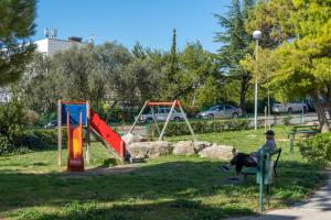 a man sitting on a bench in a park at Trstenik Beach Apartment in Split